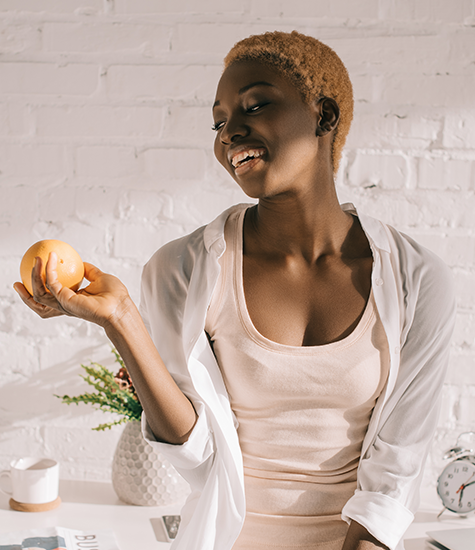Joyful model enjoying fruit Model smiling with an orange